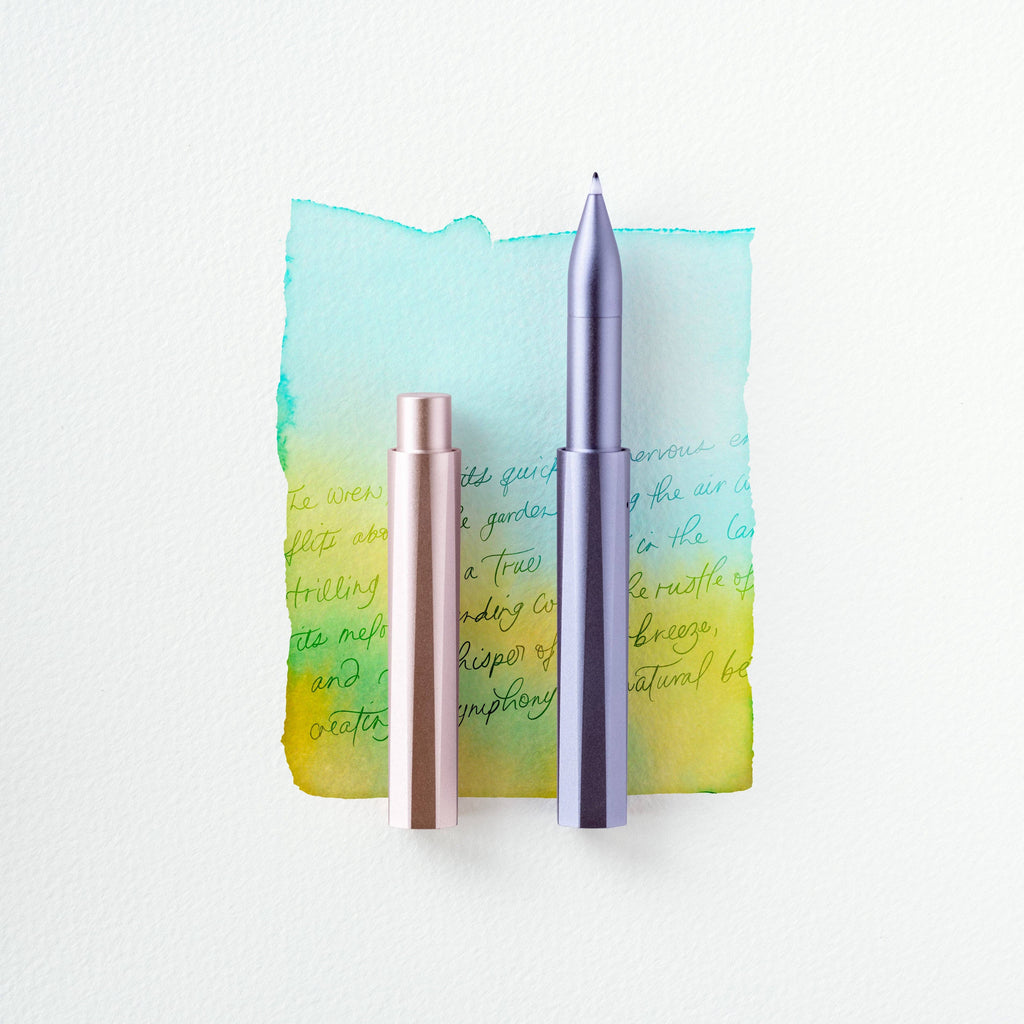 Two metallic pens on a watercolor background with text