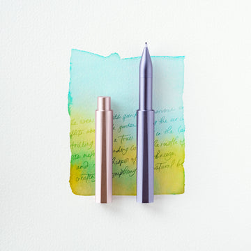 Two metallic pens on a watercolor background with text